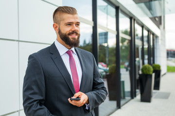 Young bearded businessman writting business e-mail using his mob