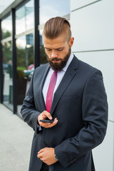 Young bearded businessman writting business e-mail using his mob