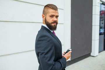 Young bearded businessman writting business e-mail using his mob