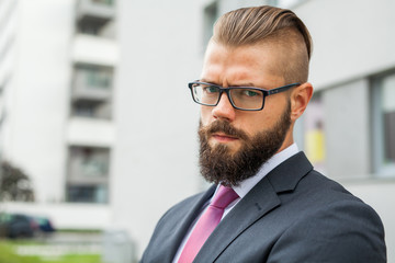 Portrait of a young focused bearded businessman outside the offi
