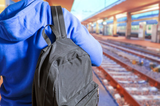 ragazzo in attesa del treno in stazione con la borsa in spalla
