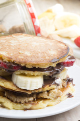 pancakes with banana, nuts and strawberry on wooden background