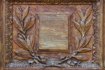 Wood carving door with empty plate with laurel branch ornament