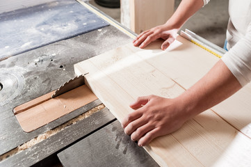 Carpenter working with Industrial tool in wood factory, circular blade with a wood board