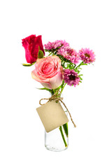 Red and pink flowers in clear bottle with label on white backgro