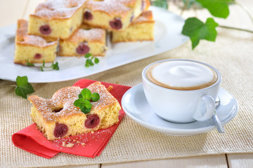 Frisch gebackener Kirschkuchen ( Blechkuchen mit versunkenen Kirschen ) mit einer Tasse Cappuccino...