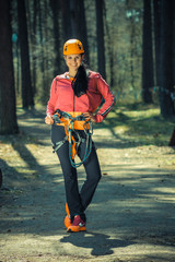 Beautiful girl in the outfit climbing climbs over obstacles between trees