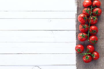 Naklejka na ściany i meble Background with tomatoes cherry branch on sackcloth and white pa