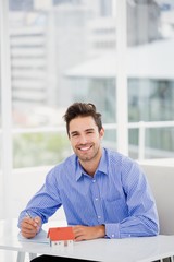 Businessman with a model house, writing on paper