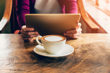woman using tablet computer in coffee shop with vintage tone.