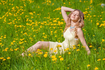 Beautiful girl on the field of dandelions is happy and enjoys the sun. sexy blonde in the spring