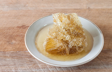 Wild Honey and honeycomb in plate on wooden table