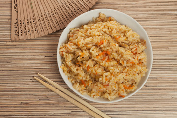 bowl of cooked rice with chopsticks and fan
