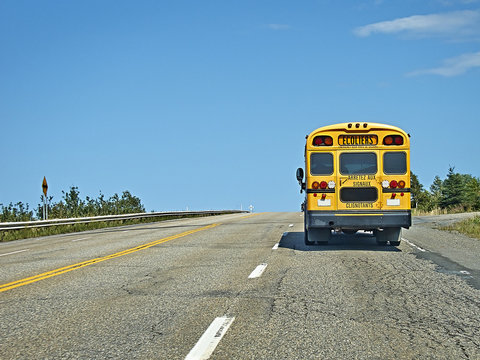 School Bus On The Road From Behind