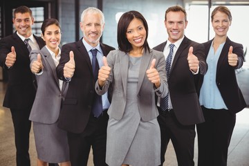 Businesspeople standing together and giving thumbs up