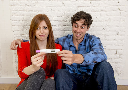 young couple in shock and surprise with scared pregnant girl reading pink positive pregnancy