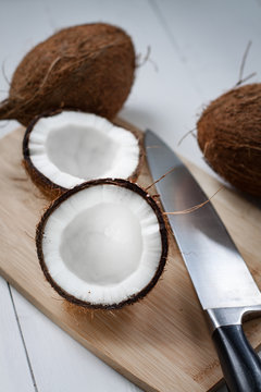 Whole and broken coconut on the white plank table.