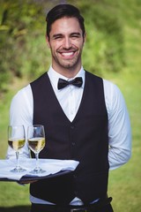 Handsome waiter holding a tray with two glasses of wine