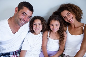 Obraz premium Portrait of family sitting together on bed