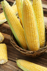 Corns in basket on a brown wooden background