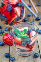 Cocktail with strawberry and blueberry on a wooden table, vertical