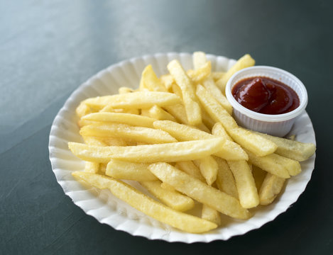 Close up French fries potatoes with ketchup on white dish.