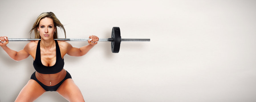 Sexy woman doing squat with barbell.