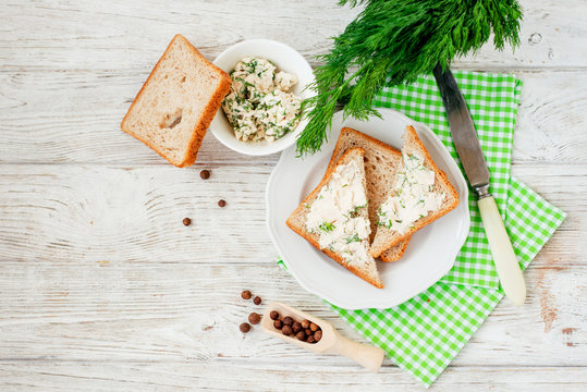 
breakfast or lunch , light sandwiches ,  rye toast with cream cheese , dill and spices on a wooden background
