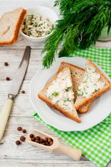 
breakfast or lunch , light sandwiches ,  rye toast with cream cheese , dill and spices on a wooden background
