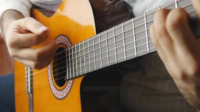 Hands playing on acoustic guitar in slow motion