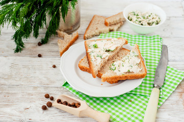 
breakfast or lunch , light sandwiches ,  rye toast with cream cheese , dill and spices on a wooden background
