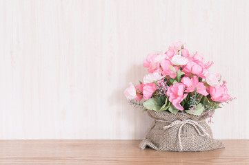 Artificial Flower bouquet in a sack on wood background