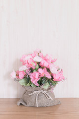 Artificial Flower bouquet in a sack on wood background