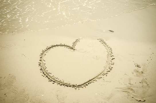 hand draw heart on sand beach