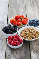 muesli and garden berries on wooden background, top view