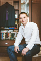 Portrait young man in white shirt. Sitting on the couch, background suit.