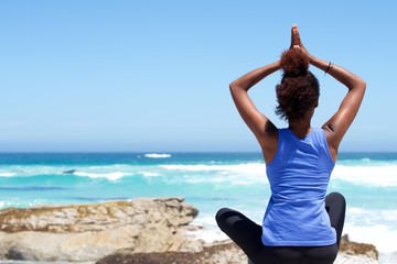 Fototapeta na wymiar Young woman sitting at the beach in yoga pose