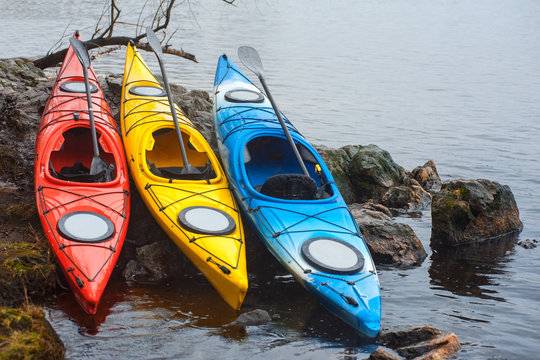 colorful fiberglass kayaks lying on the rocky shore01