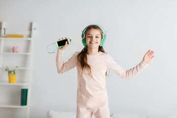 girl jumping on bed with smartphone and headphones