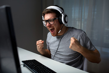 man in headset playing computer video game at home - obrazy, fototapety, plakaty