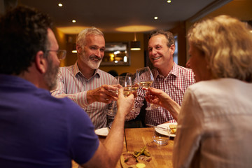 Four friends making a toast during a meal at a restaurant