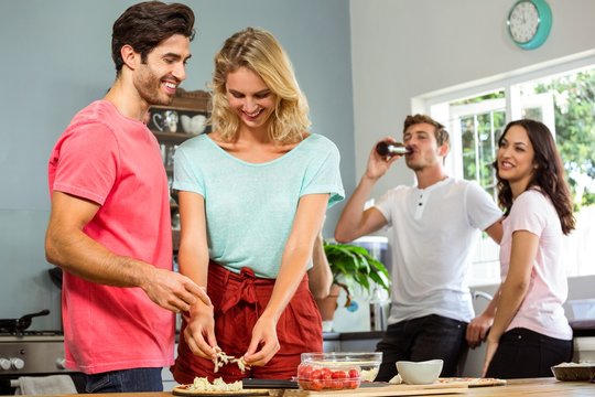 Couple preparing food while friends in background