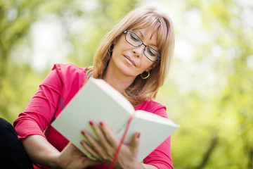 Fototapeta premium Woman reading a book in the park
