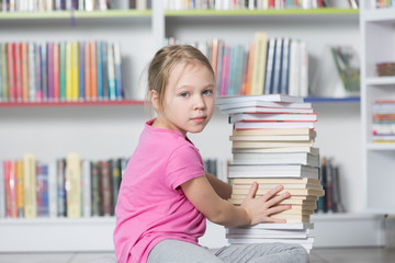 Cute girl reading book in library 
