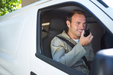 Delivery driver talking on walkie-talkie - obrazy, fototapety, plakaty