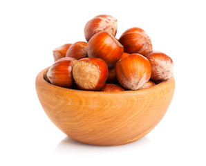 Hazelnuts in a wooden bowl on white background