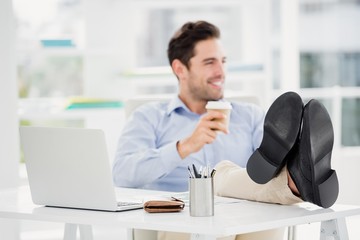 Fototapeta premium Smiling man sitting with feet on table