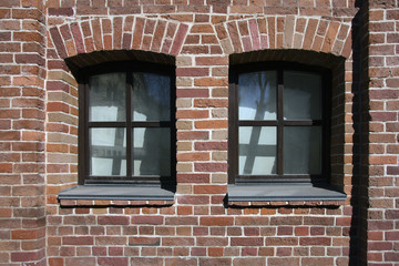 old red brick wall of building with two windows on street of Mos