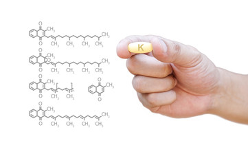 Hand holding vitamin K pill with clipping path