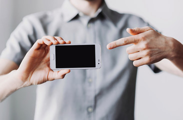 Male hand holding mobile smart phone with blank screen